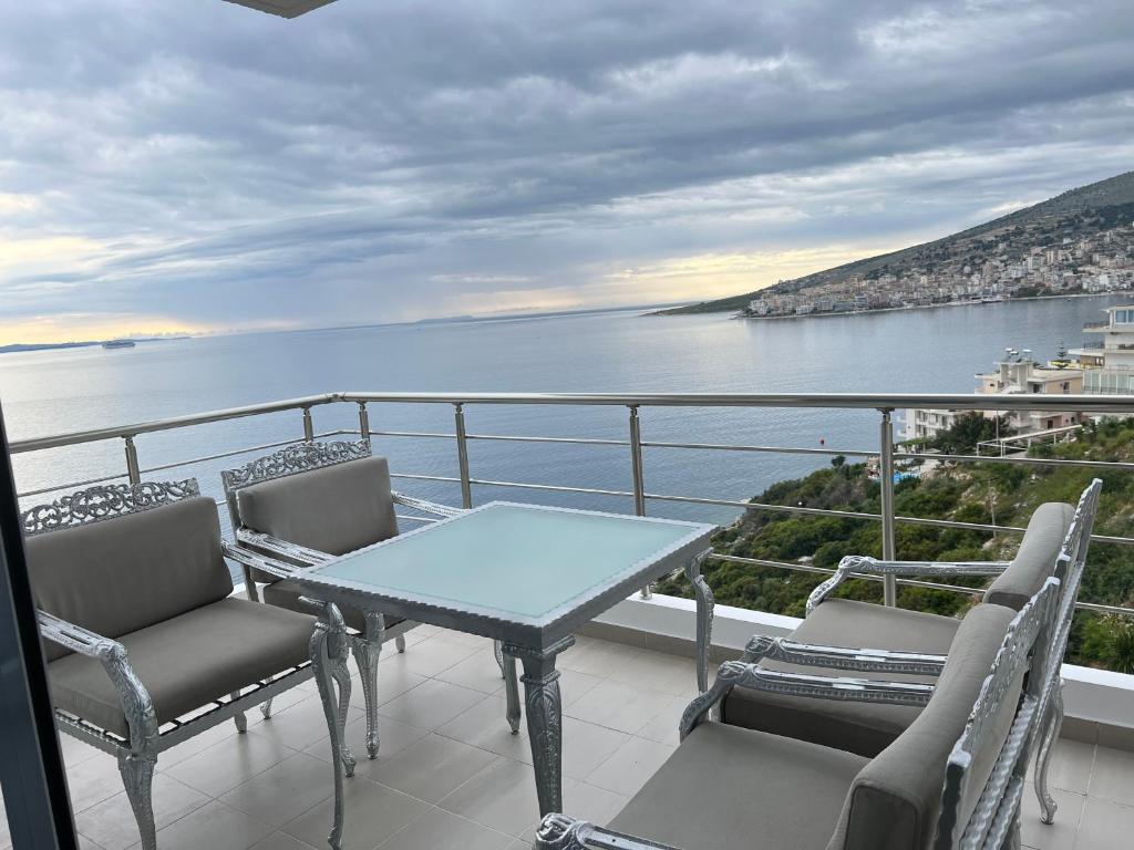un tavolo e sedie su un balcone con vista sull'acqua di Lorenso Guest House a Sarandë