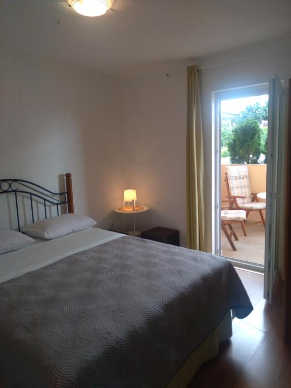 een slaapkamer met een bed en een deur naar een patio bij Apartmani Binka in Petrcane