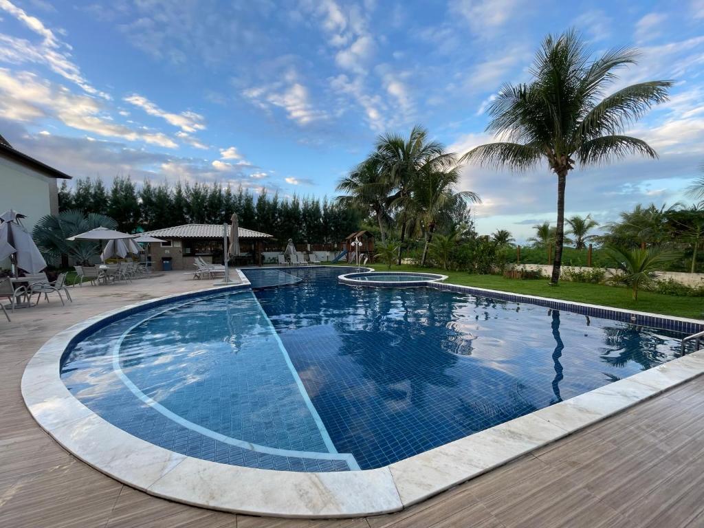 uma grande piscina com água azul e palmeiras em Itacimirim Summer Ville - Pé na Areia em Itacimirim