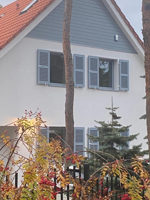 a house with blue shutters and a tree at Villa PortoBianco in Pobierowo