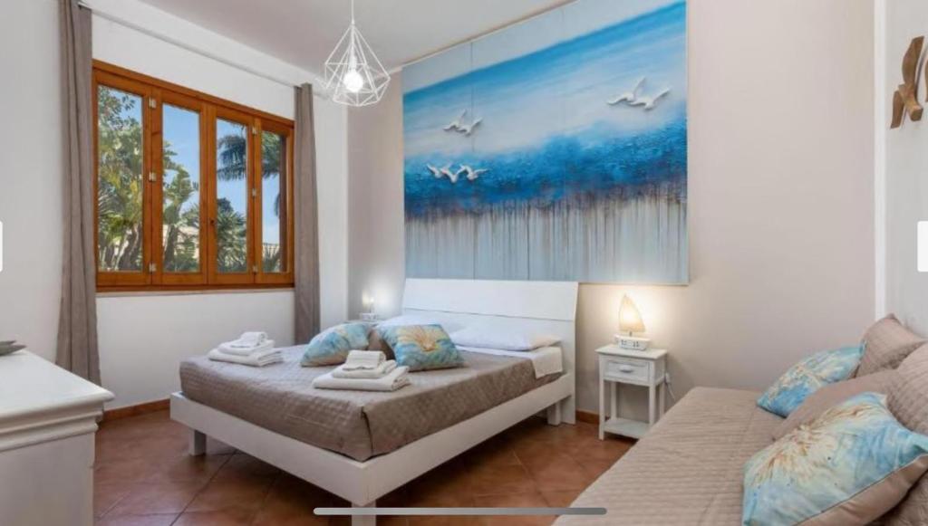 a bedroom with two beds and a painting on the wall at Blue Coral in San Vito lo Capo