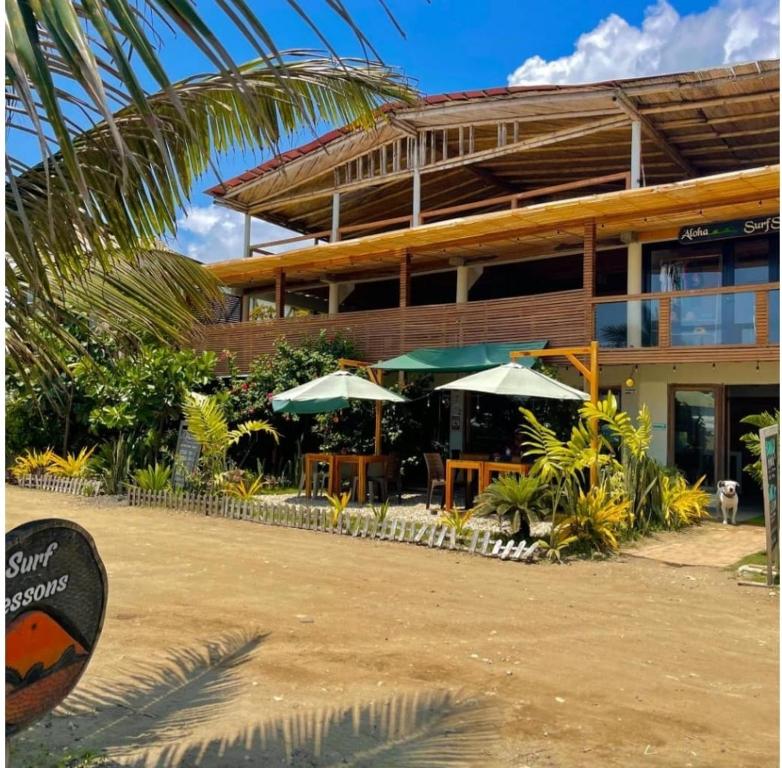 a building with tables and umbrellas in front of it at ROOM LA ISLA in Ayampe