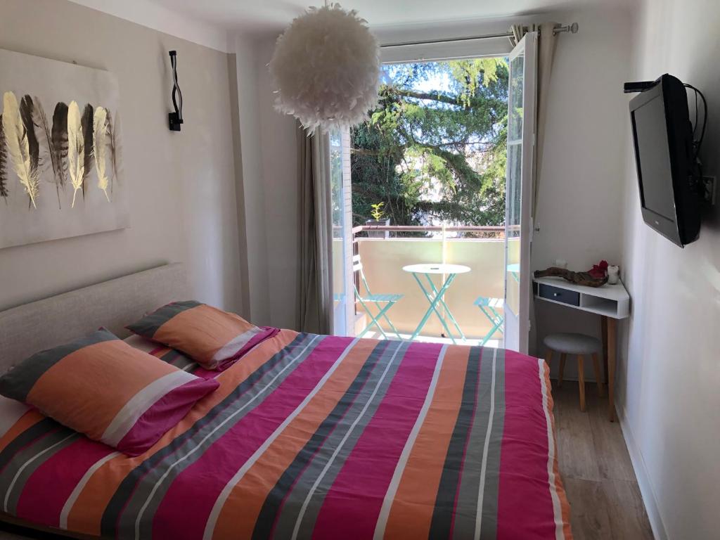um quarto com uma cama e uma varanda com uma televisão em Appart Nice Marguerite em Nice
