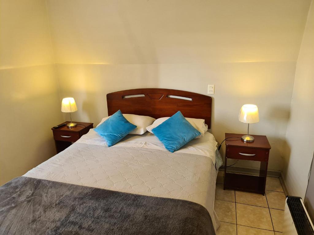1 dormitorio con 1 cama grande con almohadas azules en Frente Al Parque Arauco, en Santiago