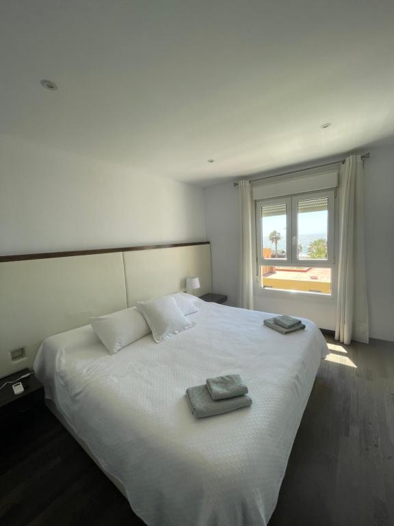 um quarto com uma cama branca com duas toalhas em Apartamento 5 EN PRIMERA LÍNEA DE PLAYA CON VISTAS AL MAR em Almeria