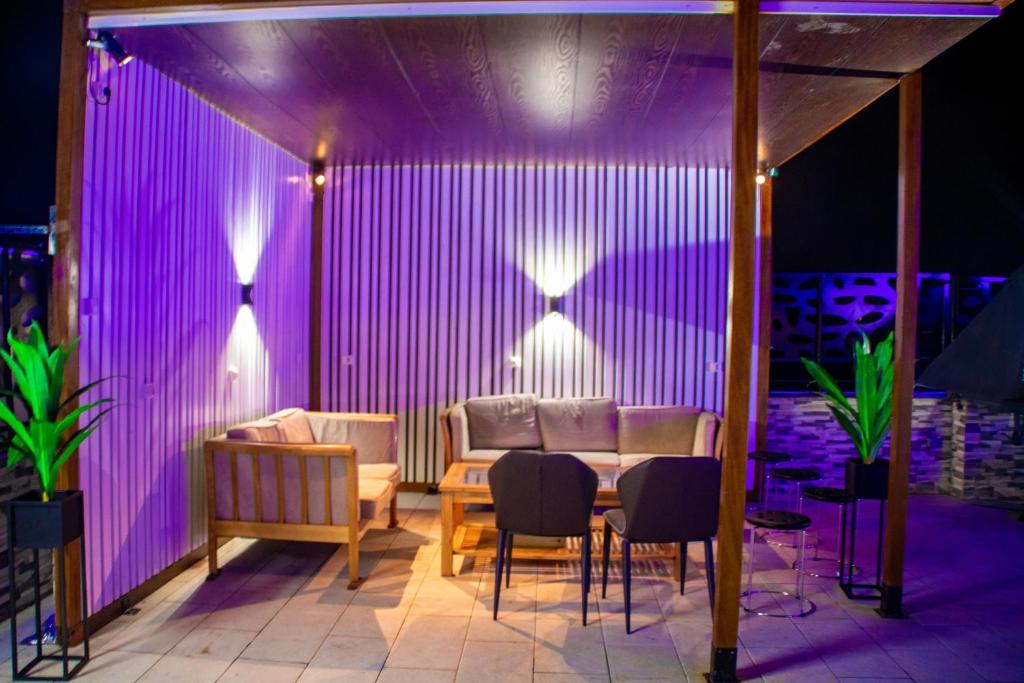 a room with a table and chairs and purple lighting at Johen Residence in Douala