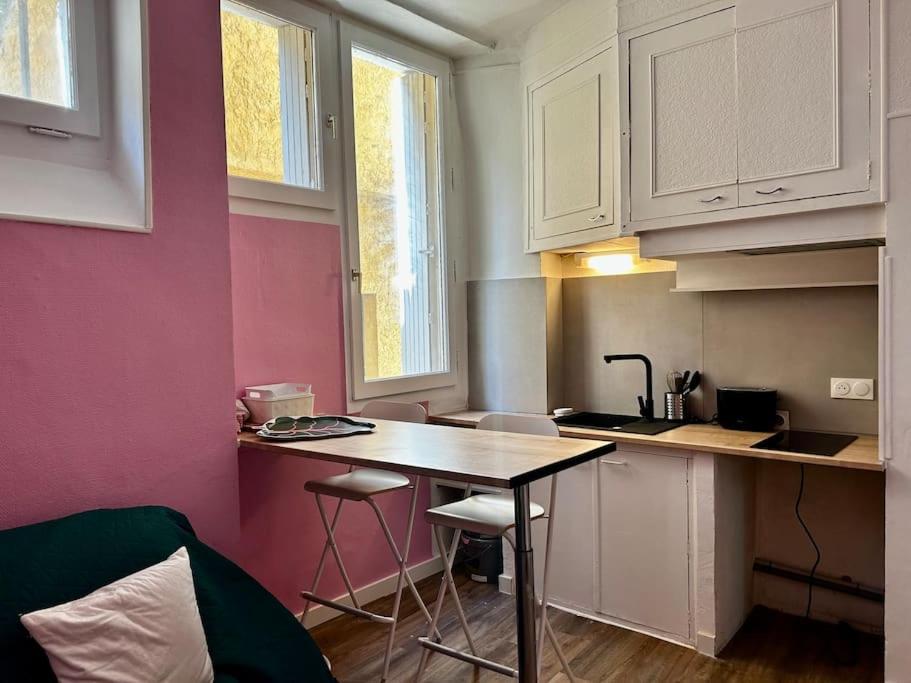 a kitchen with a table and chairs in a room at Studio place St Didier in Avignon