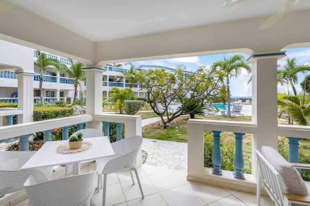une salle à manger blanche avec un balcon doté d'une table et de chaises dans l'établissement The Bay at Palm Beach, Simpson Bay, à Simpson Bay