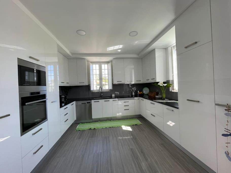 uma grande cozinha com armários brancos e piso em madeira em Casa da Celeste em Maljoga de Proença