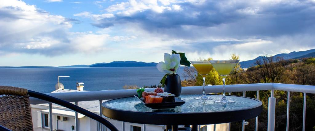 a table with two glasses and a bowl of fruit on a balcony at Apartman Tramontana in Opatija