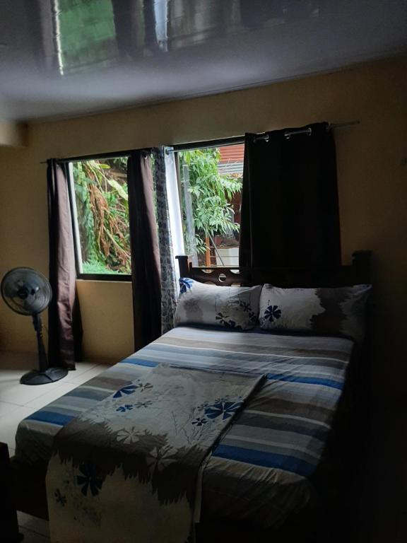 a bedroom with a bed and two windows at House la Rose Second Floor in Manuel Antonio