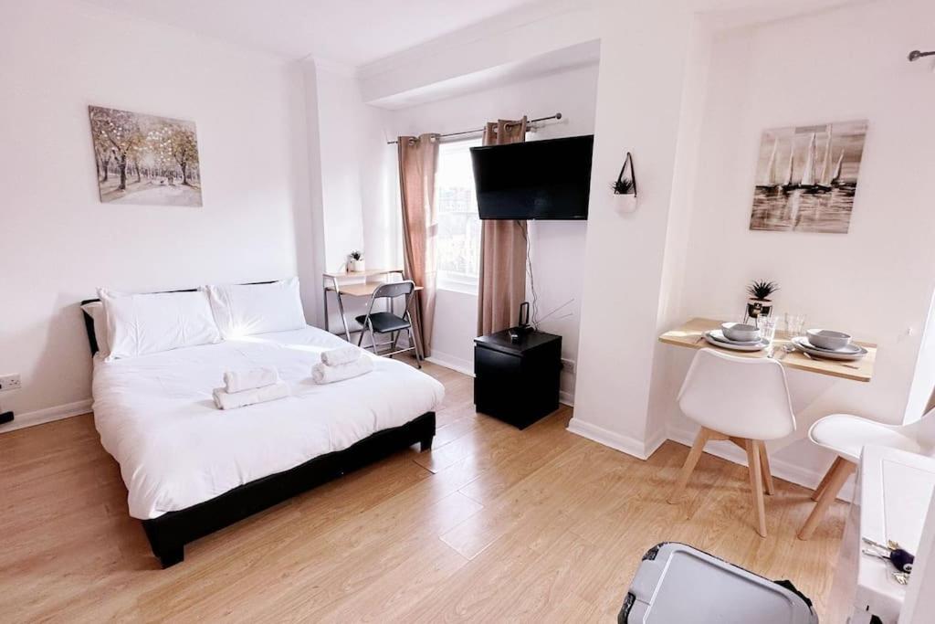a bedroom with a bed and a table and a chair at Charming Studio Flat with Private Patio Balcony in the Heart of Chelsea in London