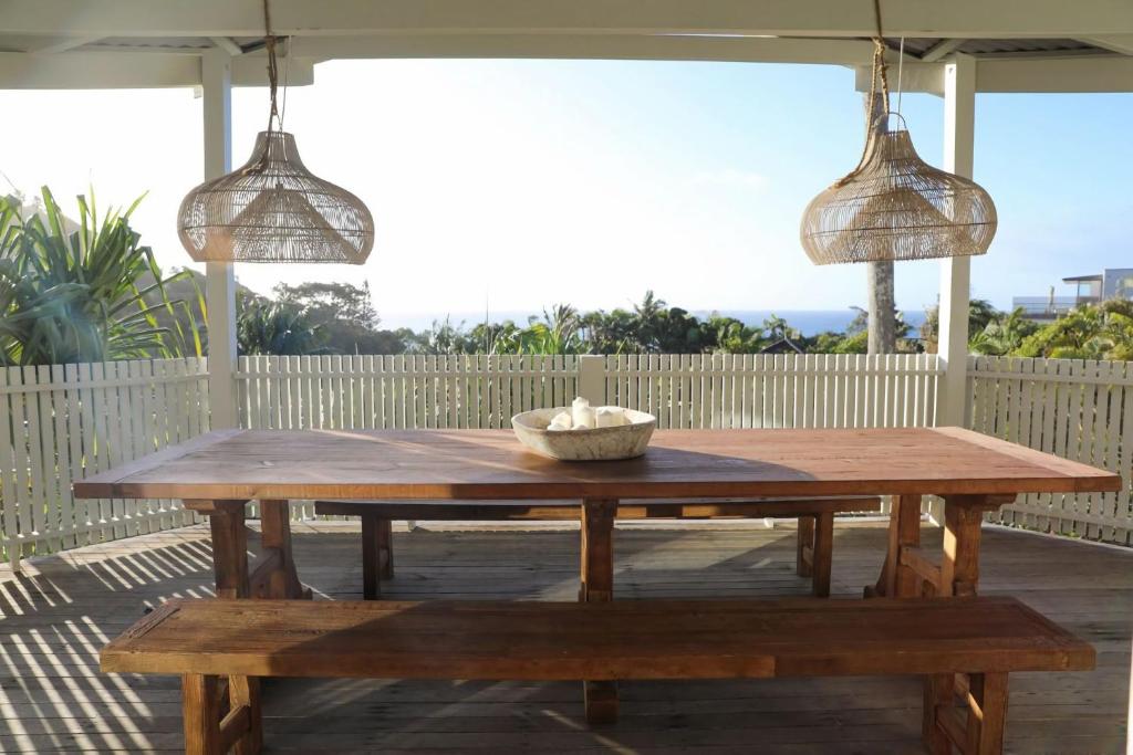 a wooden table on a patio with two pendant lights at Sirens in Byron Bay