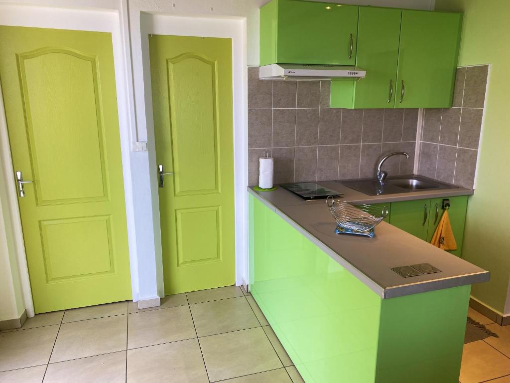 a kitchen with lime green cabinets and a sink at Appartement de 2 chambres avec vue sur la mer terrasse amenagee et wifi a Bouillante a 4 km de la plage in Bouillante