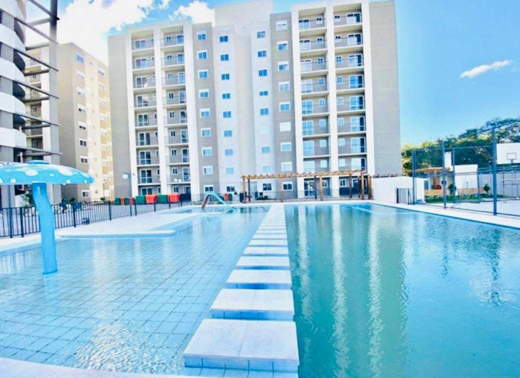 a swimming pool in front of a large building at Apartamento Acqua, 102 A, com vaga de garagem in Pelotas
