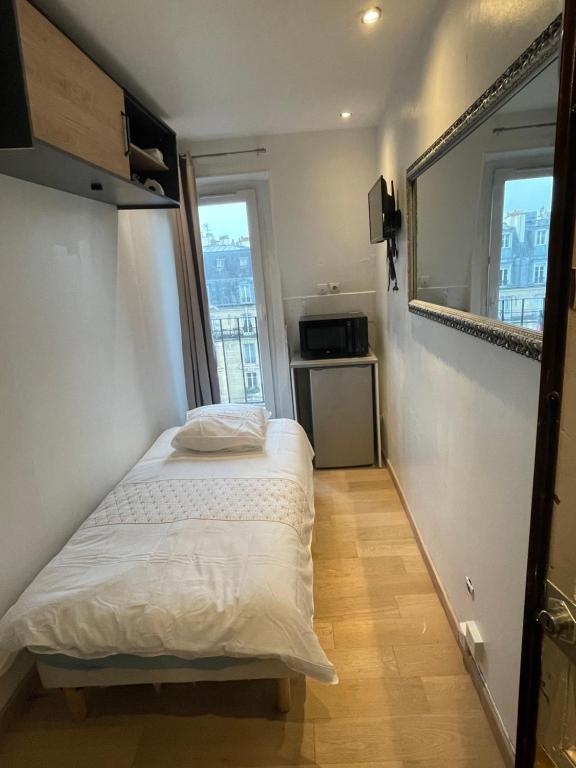 Cette petite chambre comprend un lit et deux fenêtres. dans l'établissement Douchedodo, à Paris
