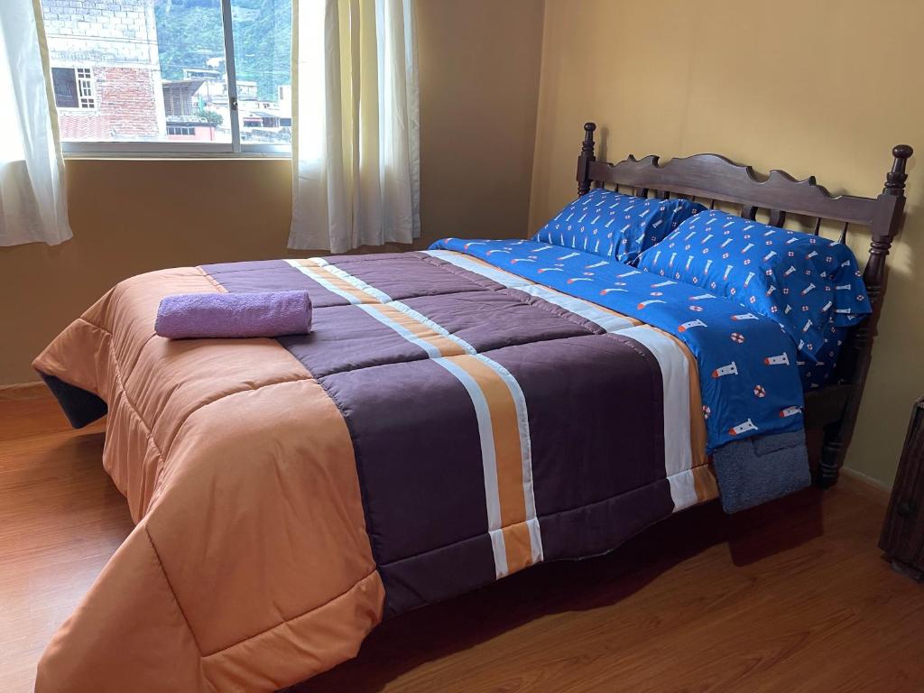 a bedroom with a large bed with a blue comforter at Departamento en el centro de la ciudad de Baños con netflix, wifi, garage gratuito y una excelente vista in Baños