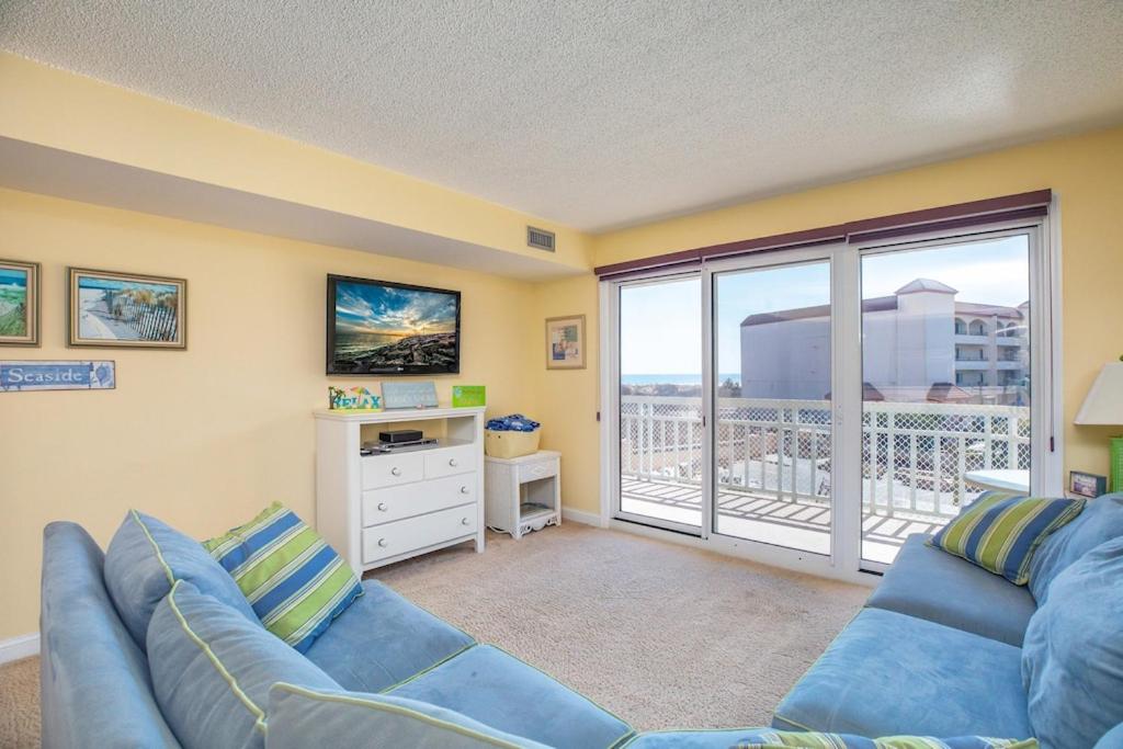 威尔伍德克拉斯特1B/1B condo with Ocean views, Resort style, Free WIFI, Few steps to the Beach!!的带蓝色沙发和阳台的客厅