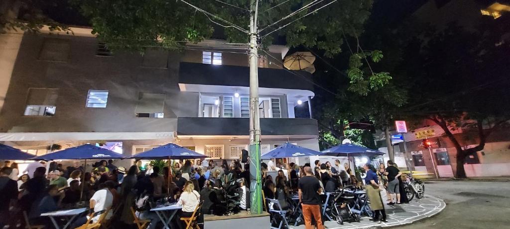 a crowd of people standing outside a building with blue umbrellas at Hostel Leblon in Rio de Janeiro