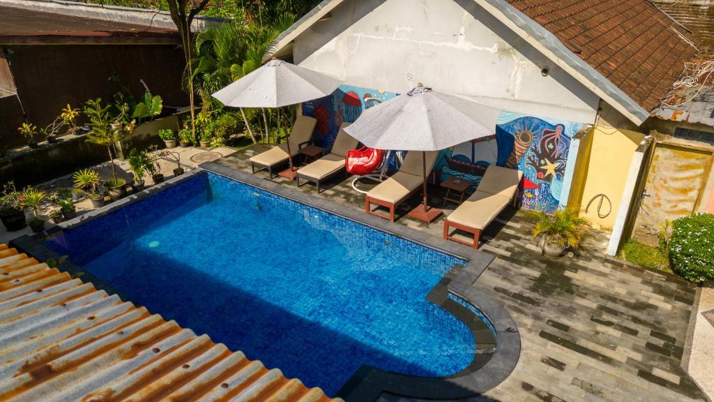 an overhead view of a swimming pool with chairs and umbrellas at Family Garden Homestay in Senggigi