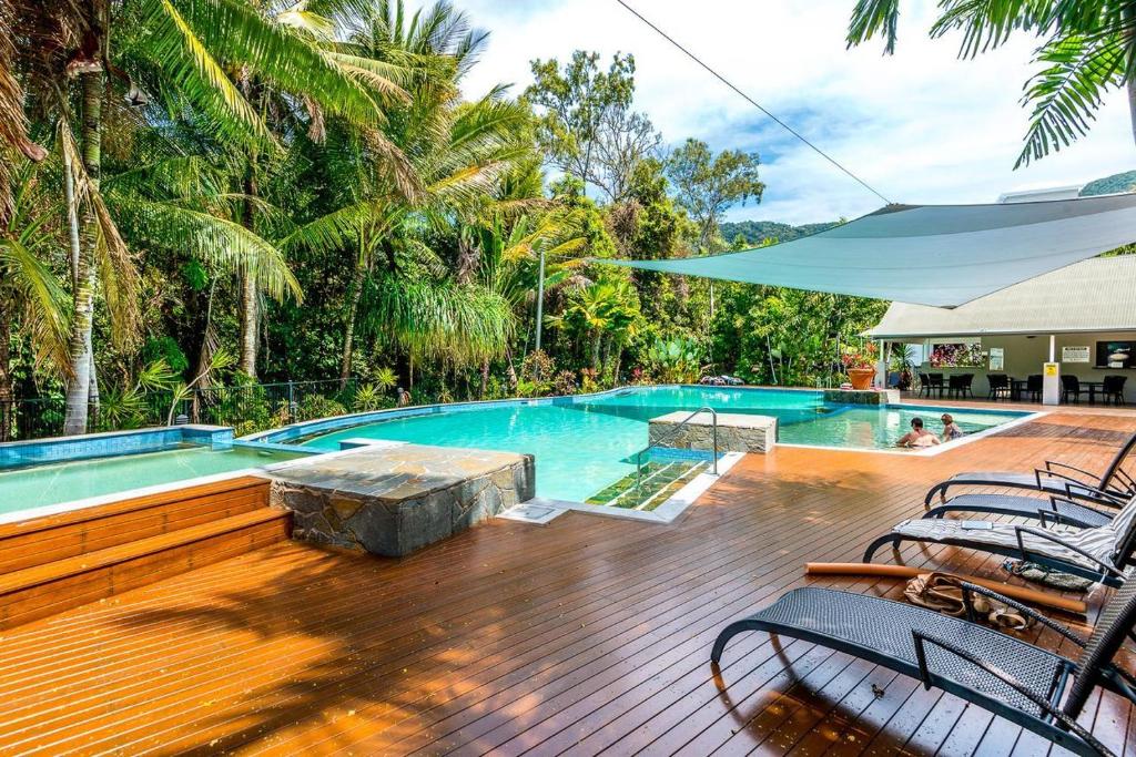 a swimming pool with chairs and an umbrella at Oasis 8 at Palm Cove in Palm Cove