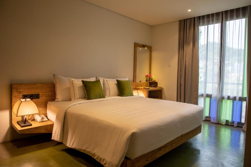 a bedroom with a large bed and a large window at Lake Avenue Hotel Kandy in Kandy