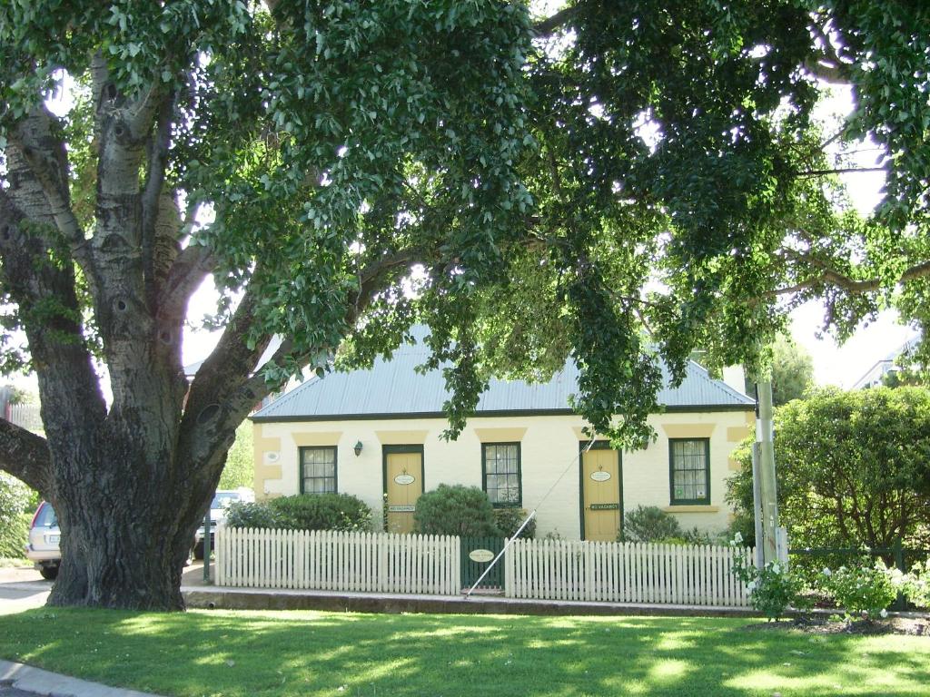 uma casa amarela com uma cerca branca e uma árvore em Bridge Cottage Sargeants & Armoury Cottages 1823 em Richmond