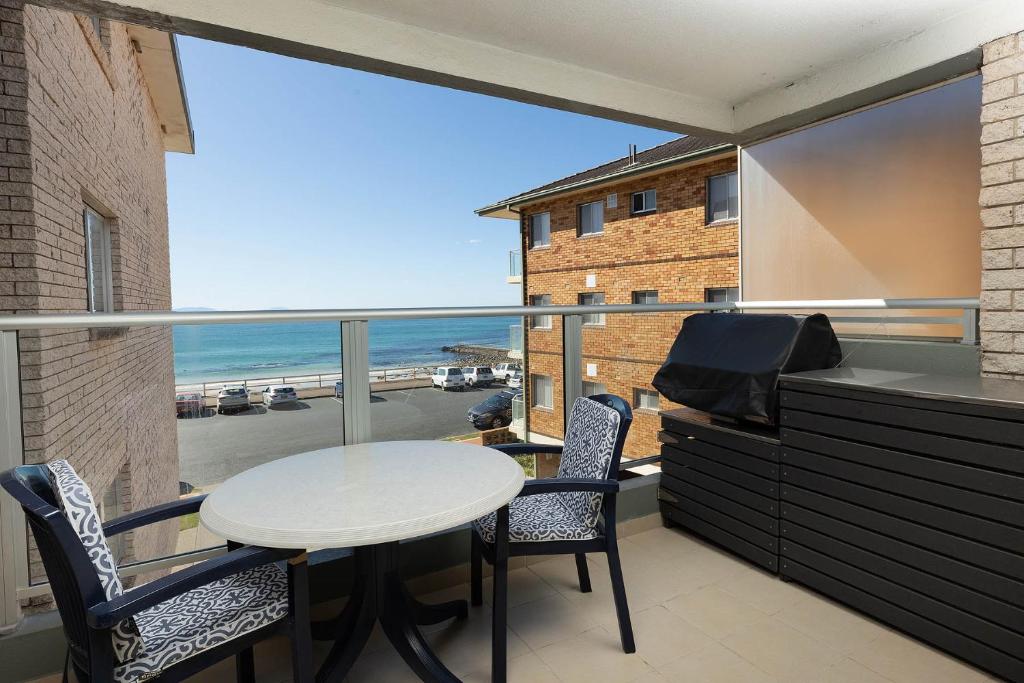 Un balcón con mesa y sillas y vista al mar. en El Sandi Unit 7, en Forster
