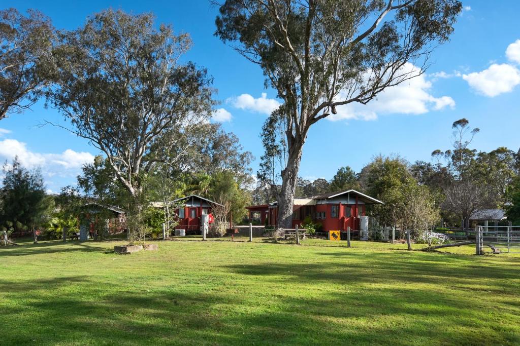 a park with trees and cabins in the background at Carriageway Retreat - Unique Red Rattler Carriages and Units in Brookfield