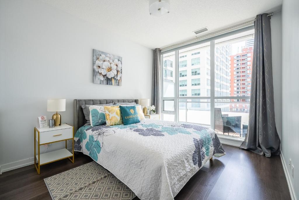 een slaapkamer met een bed en een groot raam bij Modern Lillian St Apartments by GLOBALSTAY in Toronto
