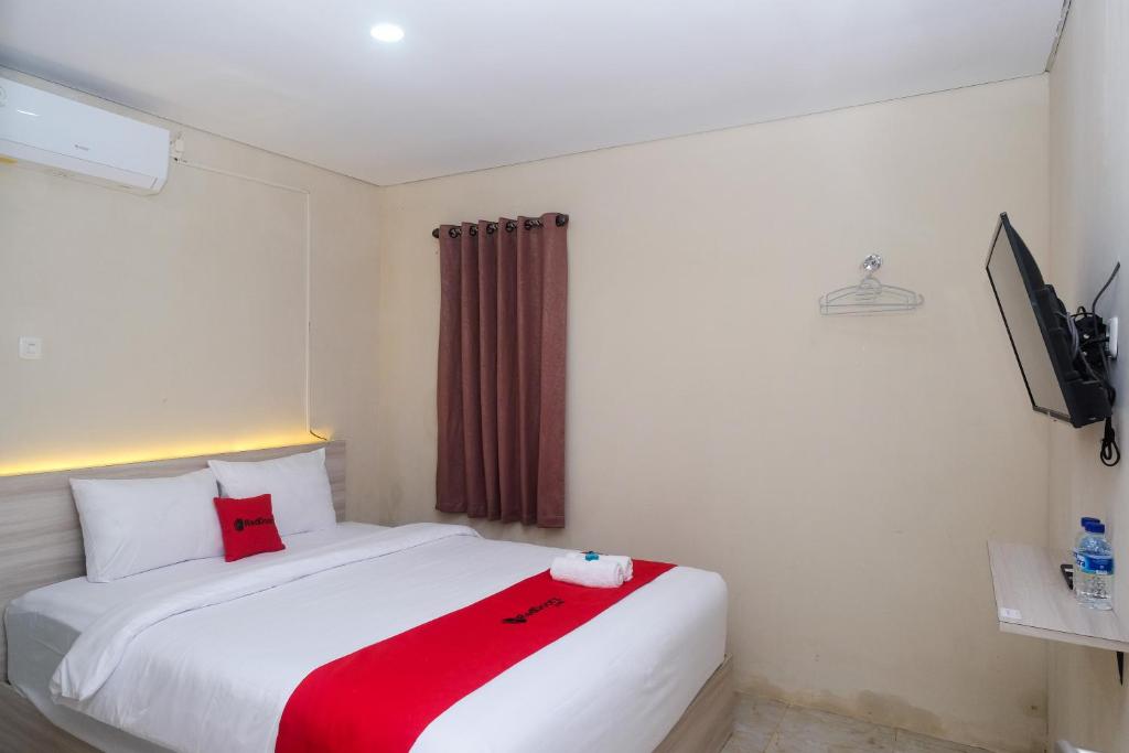 um quarto com uma cama branca e um cobertor vermelho em RedDoorz Plus near RS JIH Solo em Surakarta