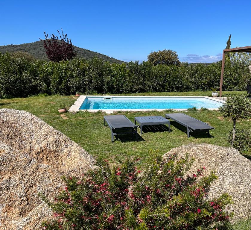 ein Pool mit zwei Tischen und zwei Bänken in einem Hof in der Unterkunft Villa CAlisti in Belgodère