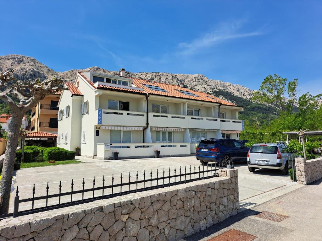 a building with cars parked in a parking lot at Apartments Fran in Baška