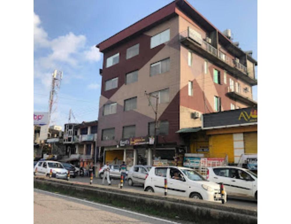 wysoki budynek z samochodami zaparkowanymi na ulicy miejskiej w obiekcie Hotel lords Highway Inn, Gagal Khas w mieście Kangra