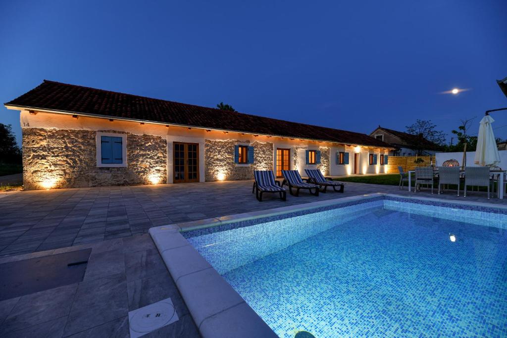 - une piscine en face d'une maison la nuit dans l'établissement Villa Martin, à Zadar