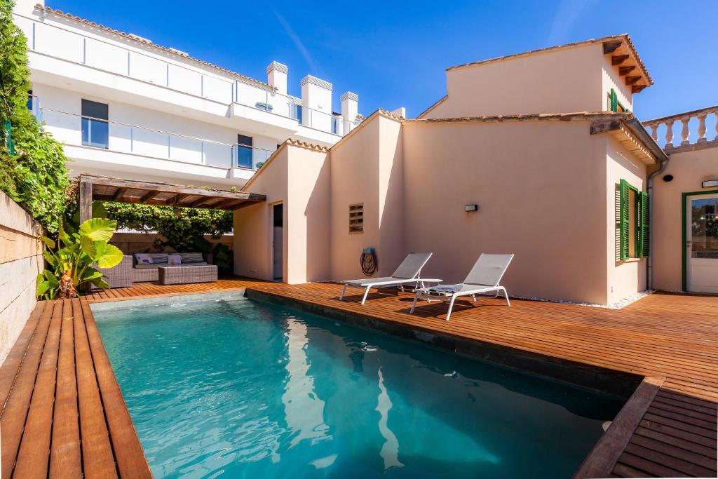 einen Pool mit zwei Stühlen und ein Haus in der Unterkunft Ca Na Aina in Cala Millor
