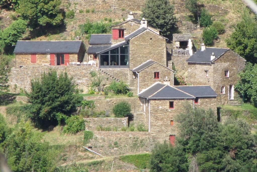 ein altes Steinhaus auf einem Hügel mit roten Türen in der Unterkunft Hameau en cévennes Location Gîte de luxe in Saint-Étienne-Vallée-Française