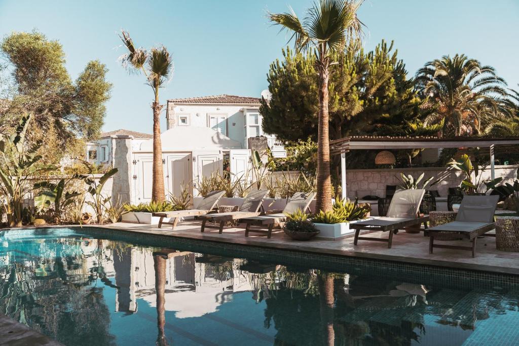 a pool with chairs and palm trees next to a house at ARTOTEL in Alaçatı