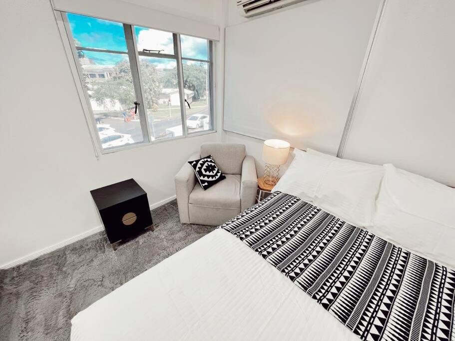 a bedroom with a bed and a chair and a window at Gladstone Gem 3 - Suva CBD 2bd Apt in Suva