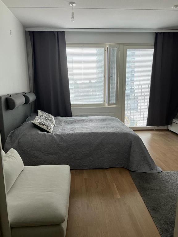 a bedroom with a bed and a couch and two windows at City apartment nearby Airport in Vantaa