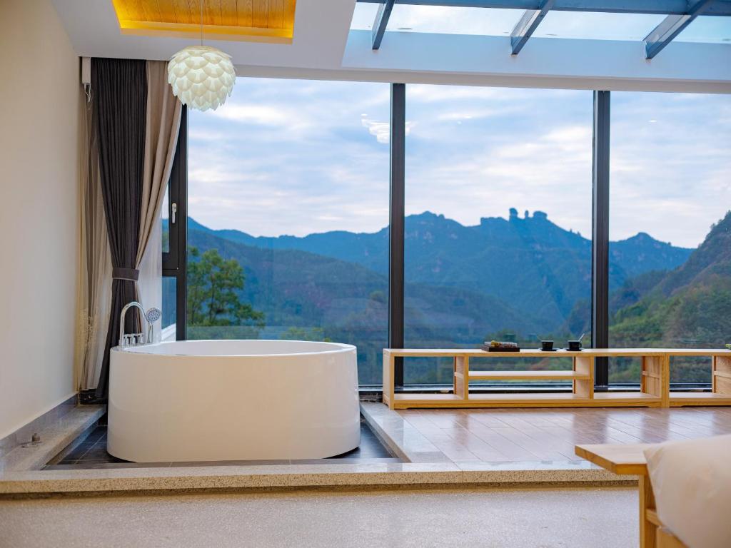 La salle de bains est pourvue d'une baignoire devant une grande fenêtre. dans l'établissement Drunken Valley Manor - Zhangjiajie National Forest Park, à Zhangjiajie