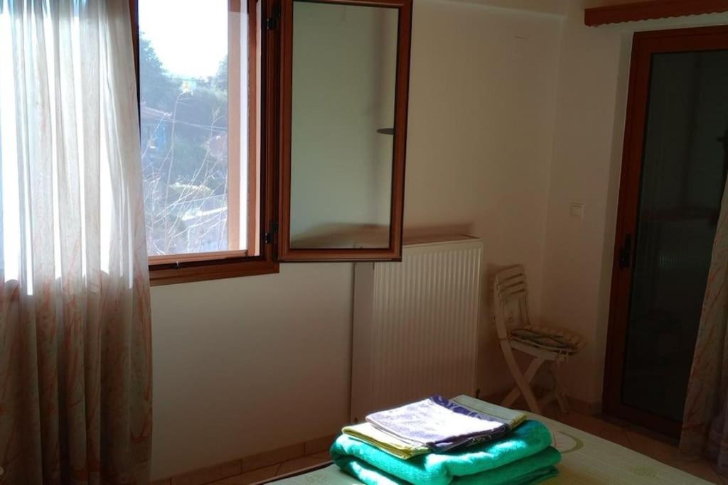 Cette chambre dispose d'une fenêtre et d'une table avec des serviettes. dans l'établissement THE BEST VIEW Of arini village, à Zakharo