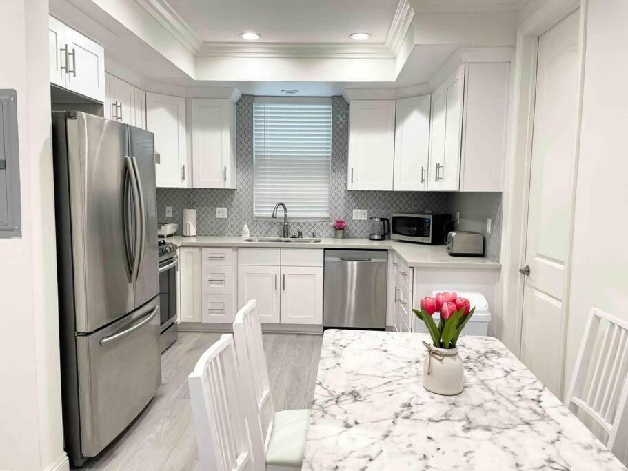 a kitchen with white cabinets and a table with flowers on it at Charming 3B3B Townhome (Relax & Family Friendly) in Pasadena