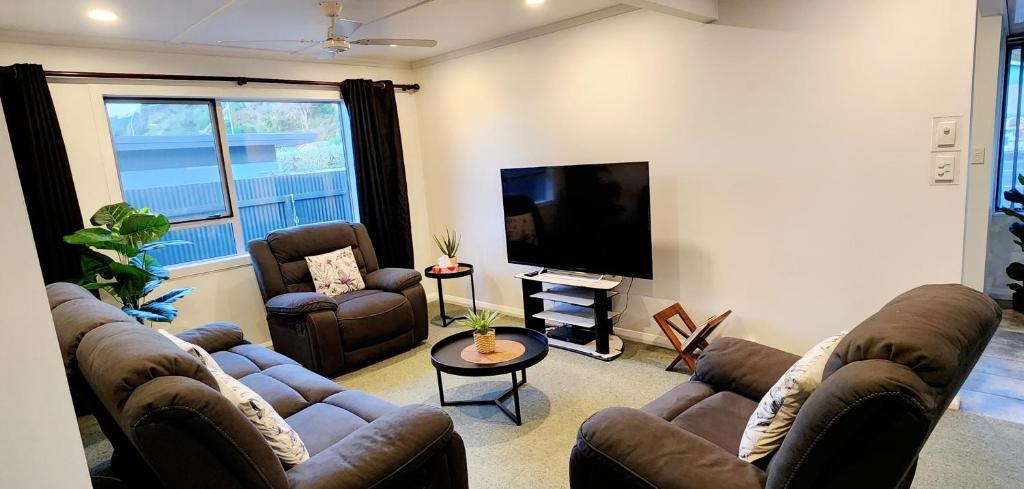 a living room with couches and a flat screen tv at Ahuriri Escape - Home Away Home, Entire Bungalow in Napier