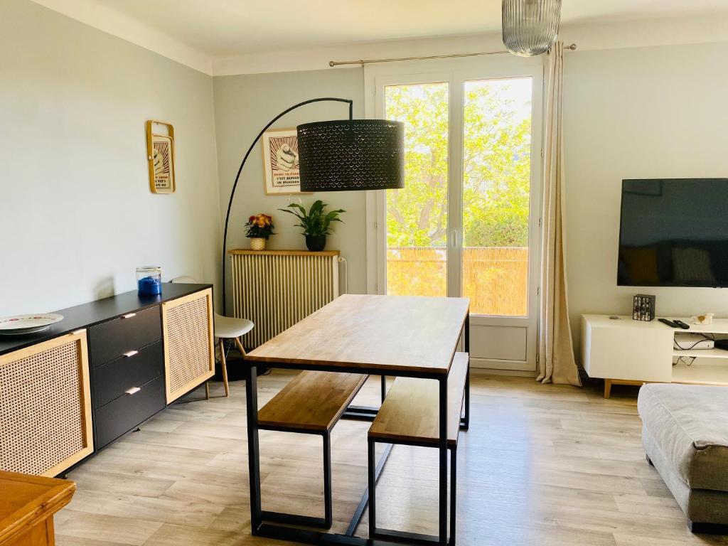 ein Wohnzimmer mit einem Tisch und einem Sofa in der Unterkunft Superbe appartement 2 chambres, clim, quartier calme entre la mer et les calanques in Marseille