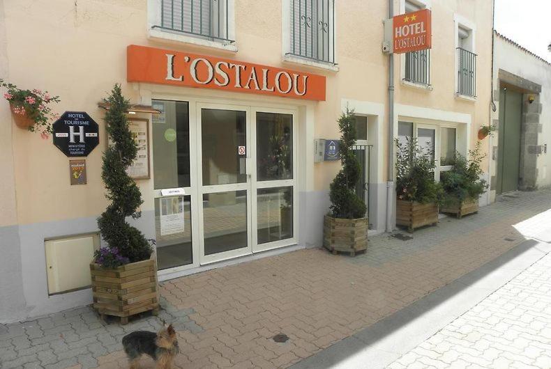 a cat is standing outside of a store at L’Ostalou in Issoire