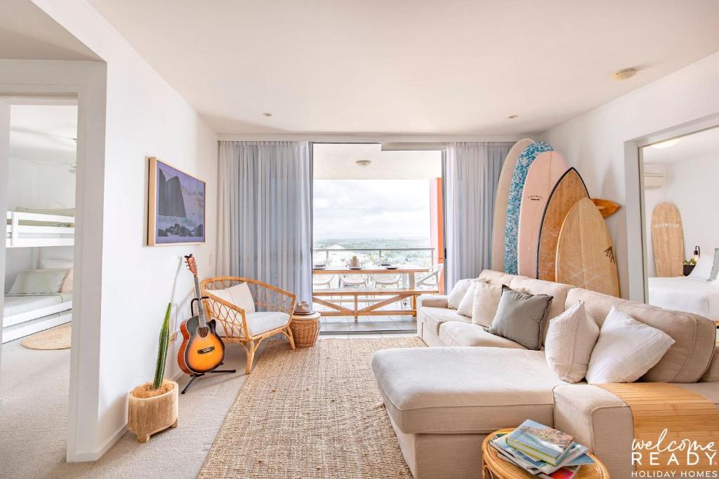 a living room with a couch and a guitar at Kings Beach Surf Retreat - Beautiful Views in Caloundra