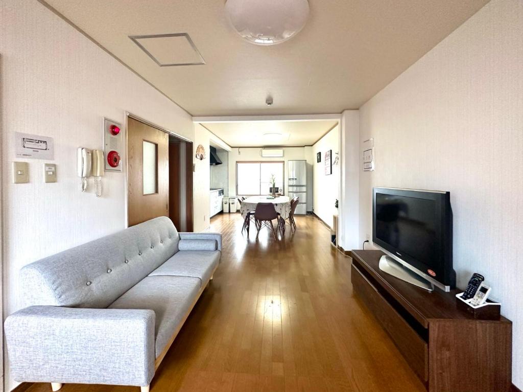 uma sala de estar com um sofá e uma televisão de ecrã plano em Shirakabanoyado - Kujo em Osaka