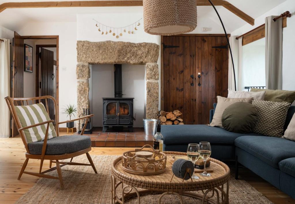 a living room with a blue couch and a fireplace at Porthcurno Barns, The Big Barn - Spacious & cosy cottage, walk to Porthcurno beach, Pedn Vouder & Minack Theatre in Penzance