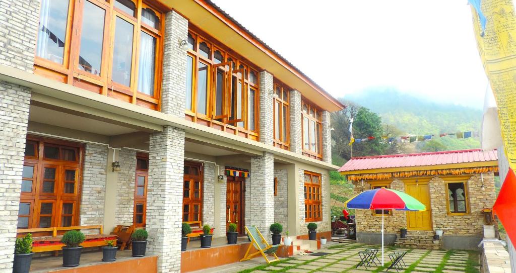 a building with a patio with a colorful umbrella at Kharjap Homestay in Dirang Dzong